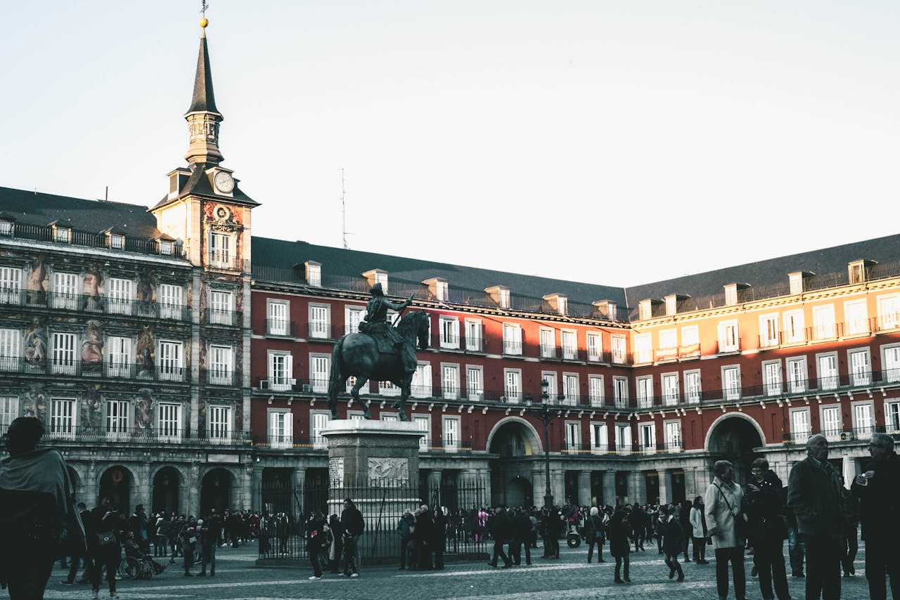 A lively scene at Plaza Mayor, Madrid, featuring historic architecture and a statue.